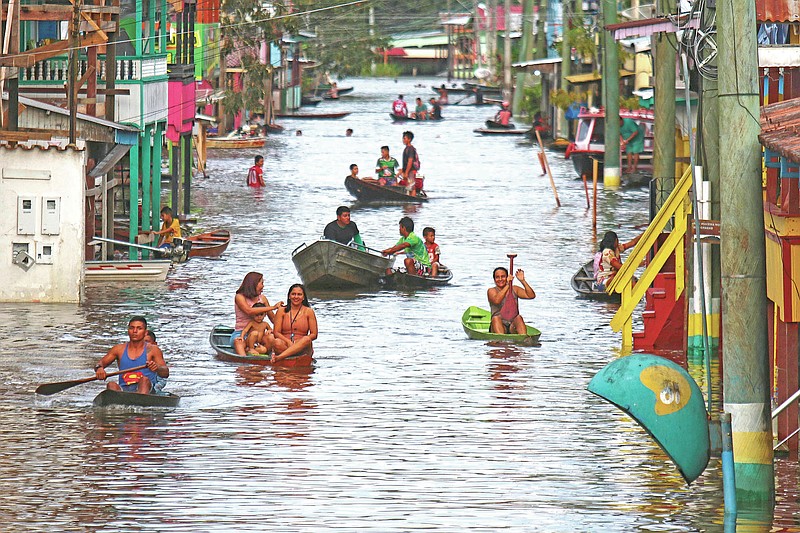 Residents navigate a flooded street in Anama, Amazonas state, Brazil, Thursday, May 13, 2021.  (AP Photo/Edmar Barros)
