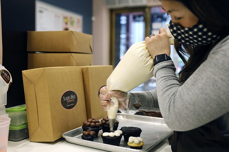 Sugar Bliss Bakery owner Teresa Ging prepares one of her bakery items in her shop in Chicago's famed Loop, Tuesday, May 4, 2021. In many downtown areas where companies closed their offices and commuting ground to a halt, sandwich shops, bakeries and other small businesses are waiting with guarded optimism for their customers to return. (AP Photo/Shafkat Anowar)