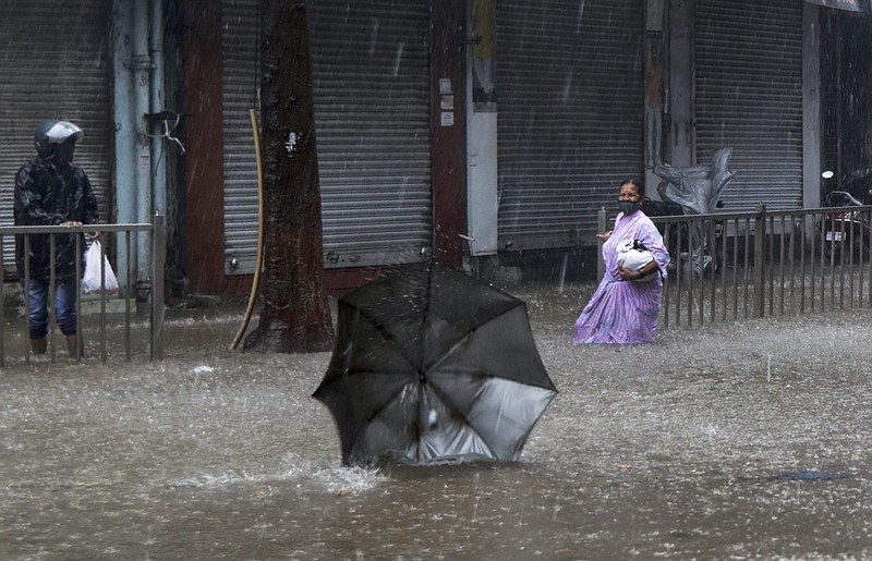 A woman helplessly watches her umbrella fly away in the wind during a heavy rain in Mumbai, India, Monday, May 17, 2021.  Cyclone Tauktae, roaring in the Arabian Sea was moving toward India's western coast on Monday as authorities tried to evacuate hundreds of thousands of people and suspended COVID-19 vaccinations in one state. (AP Photo/Rajanish Kakade)