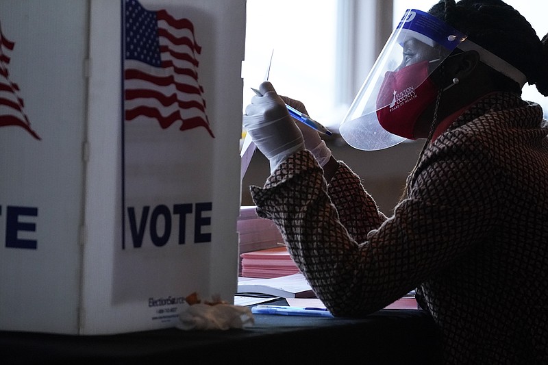 FILE - In this Nov. 3, 2020, file photo, a poll worker talks to a voter before they vote on a paper ballot on Election Day in Atlanta. (Democrats are revising key sections of their sweeping legislation to overhaul U.S. elections, hoping to address the concerns raised by state and local election officials even as they face daunting odds of passing the bill through Congress. AP Photo/Brynn Anderson, File)