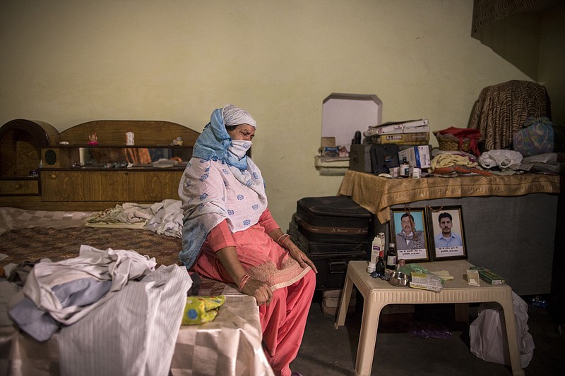 Suresh Devi, the widow of Kumarsain Nain, weeps next to his portrait, at left, at her home in the village of Bassi, Uttar Pradesh, India in 2021. MUST CREDIT: Bloomberg photo by Anindito Mukherjee
