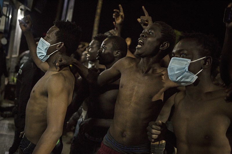 A group of migrants arrive outside a holding centre for migrants the Spanish North African enclave of Melilla, Spain, Tuesday May 18, 2021. A large group of Africans crossed into Melilla on the North African coast in the early hours by jumping over the enclave's double fence. Spain said around 6,000 people had earlier crossed the border into Spain's other North Africa enclave of Ceuta. (AP Photo/Javier Bernardo)