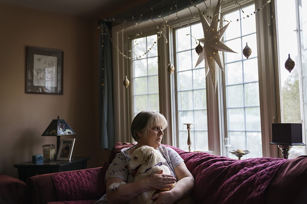 Ellen Booth, 57, who is studying to become a certified medical coder, sits with her dog, Rumble, at her home in Coventry, R.I., Monday, May 17, 2021. When the restaurant she worked for closed last year, Booth said it gave her "the kick I needed." She started a year-long class to learn to be a medical coder. When her unemployment benefits ran out two months ago, she started drawing on her retirement funds. Booth hopes to pass her upcoming exam and soon hit the job market. (AP Photo/David Goldman)