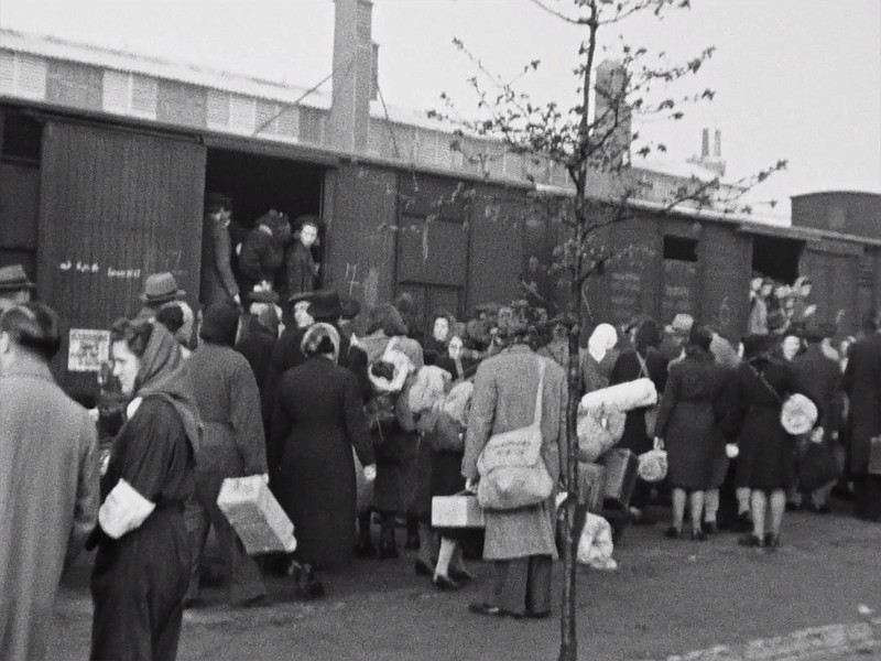 In an undated image, Bernard Hartlooper (center), a buyer and warehouse clerk, waits to board a Nazi transport with his satchel over his shoulder. The enhanced footage helped the researchers identify people who had inscribed their name on their possessions.
(Collection of NIOD/Sound and Vision the Netherlands via The New York Times)