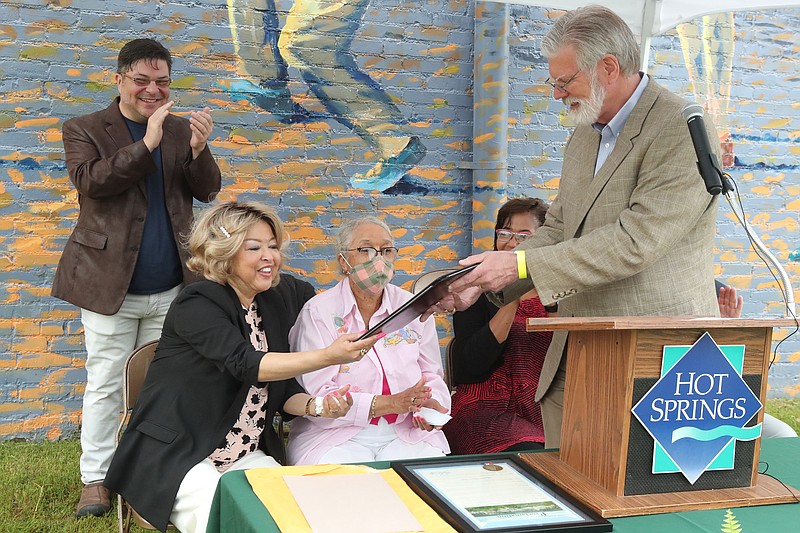 Stephen Koch, of Little Rock, back, left, reacts as Mayor Pat McCabe presents a proclamation to Sherry Glover Thompson, of Laurel, Md., and Helen Ruth Collins, of Coden, Ala., at a dedication ceremony for a park named in honor of Henry Glover. - Photo by Richard Rasmussen of The Sentinel-Record