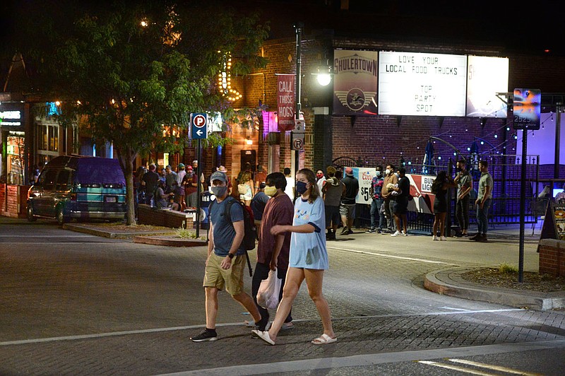 A group of people cross the street Aug. 28 on Dickson Street in Fayetteville. Fayetteville and Rogers will reconsider their mask ordinances at upcoming City Council meetings.
(File photo/NWA Democrat-Gazette/Andy Shupe)