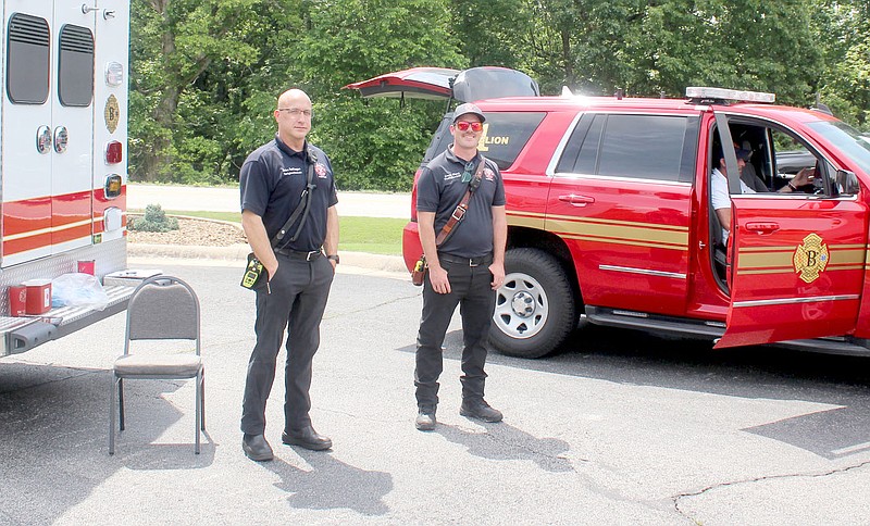 Keith Bryant/The Weekly Vista
Firefighters Brian Heffington, left, and Avery Sharp as well as Battalion Chief Ronnie Crupper, working in the truck, stand waiting for patients at a pop-up COVID-19 vaccine clinic during Sunday's farmers market.