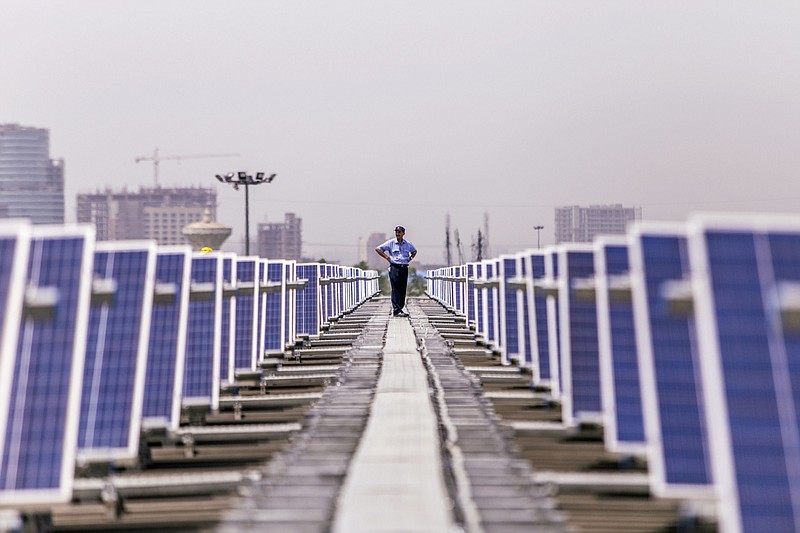 A security guard stands between solar panels implemented by Amplus Solar on the roof of the Yamaha Motor Co. plant in Surajpur, Uttar Pradesh, India, on July 20, 2016. MUST CREDIT: Bloomberg photo by Prashanth Vishwanathan.