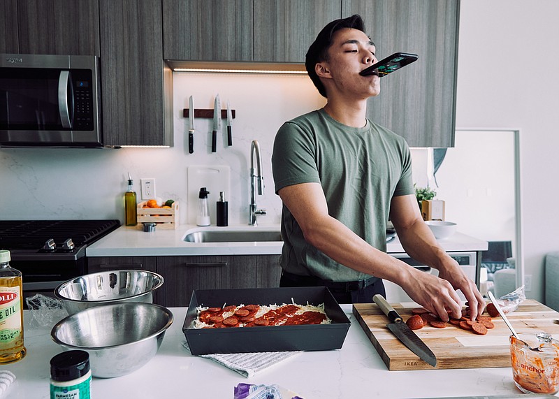 Newton Nguyen films a cooking video for TikTok at his home in Los Angeles, May 17, 2021. Nguyen is one of the best-known food creators on TikTok, with almost seven million followers. (The New York Times/Adam Amengual)