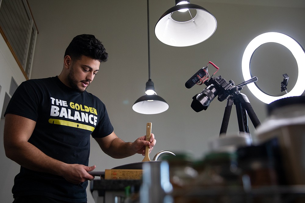 Ahmad Alzahabi, who runs his own food media company called the Golden Balance, films a cooking video at his home in Flint, Mich., May 17, 2021. "Recipes that are going viral on other social platforms are just visually appealing, you drool over them, but you never make them," said Alzahabi. "TikTok has allowed people to document their family gatherings, what they make at home. It doesn't have to look as pretty." (The New York Times/Emily Elconin)
