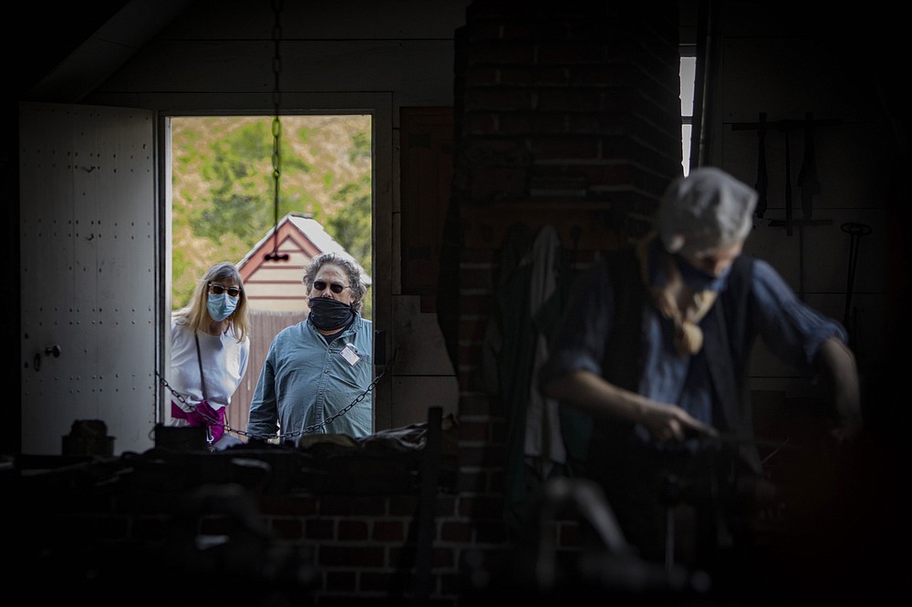Visitors watch as Broadus Thompson works in the blacksmith shop. (For The Washington Post/Julia Rendleman)