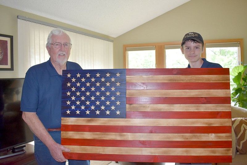 Rachel Dickerson/The Weekly Vista Don Lowe, left, and grandson Jeremiah Lowe are pictured with a large wooden American flag that they made together. They make many varieties of flags with different logos on the union.