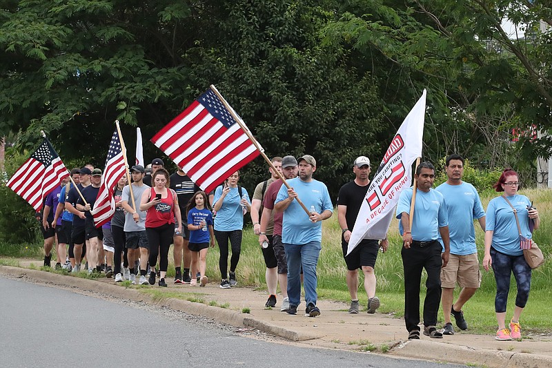 East Coast Carry the Load representatives, Hot Springs police and community members walk along Central Avenue Wednesday as part of the annual 15,500-mile national relay that began in West Point, N.Y. - Photo by Richard Rasmussen of The Sentinel-Record
