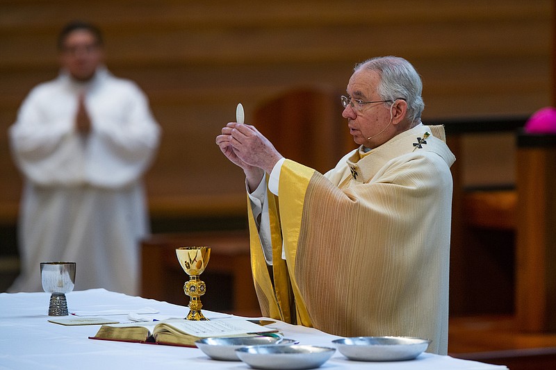 FILE - In this Sunday, June 7, 2020 file photo, Archbishop Jose H. Gomez holds a Communion wafer as he celebrates the the Solemnity of the Most Holy Trinity, a Mass with churchgoers present at the Cathedral of Our Lady of the Angels in downtown Los Angeles. Despite calls from some of its members for a delay, the U.S. Conference of Catholic Bishops plans to devote part of its national meeting in June 2021 to the sensitive issue of which Catholics are worthy of receiving Communion. (AP Photo/Damian Dovarganes, File)