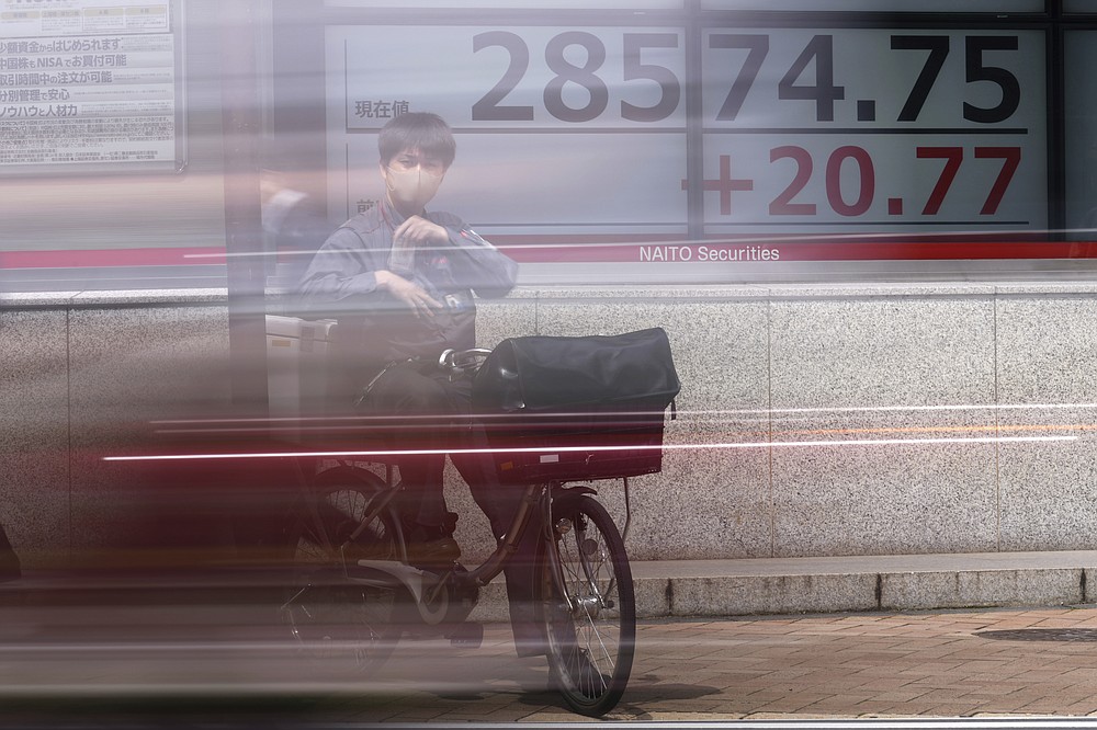 A man wearing a protective mask rides a bicycle in front of an electronic stock board showing Japan's Nikkei 225 index at a securities firm Wednesday, May 26, 2021, in Tokyo. Asian stock markets rose Wednesday as inflation fears eased and investors looked ahead to U.S. data that are expected to show economic growth accelerating. (AP Photo/Eugene Hoshiko)