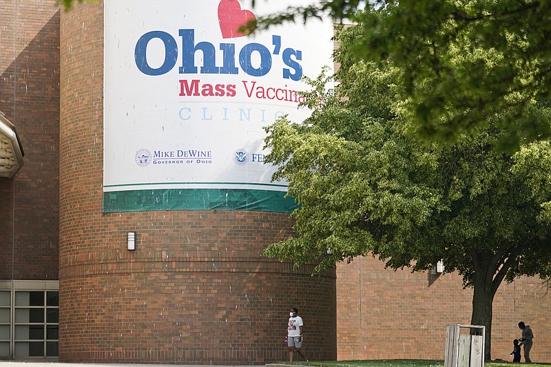 People walk past sign displayed for Ohio's covid-19 mass vaccination clinic at Cleveland State University, Tuesday, May 25, 2021, in Cleveland. Nearly 2.8 million residents have registered for Ohio's Vax-a-Million vaccination incentive program, with participants hoping to win either the $1 million prize for adults or a full-ride college scholarship for children, Gov. Mike DeWine announced Monday, May 24. The winners will be announced Wednesday night at the end of the Ohio Lottery's Cash Explosion TV show, and then each Wednesday for the next four weeks. (AP Photo/Tony Dejak)