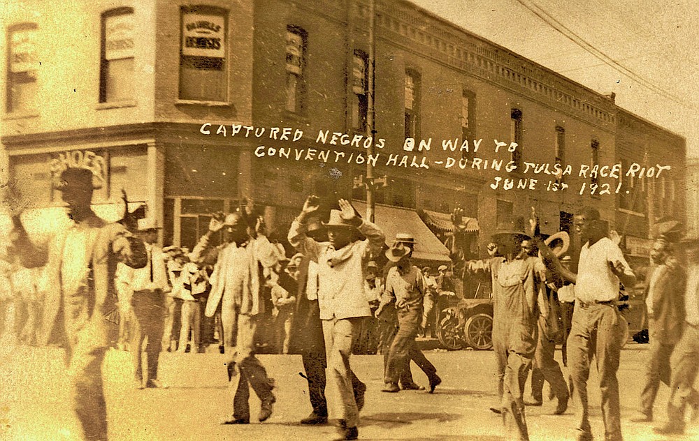 In this photo provided by the Department of Special Collections, McFarlin Library, The University of Tulsa, a group of Black men are marched past the corner of 2nd and Main Streets in Tulsa, Okla., under armed guard during the Tulsa Race Massacre on June 1, 1921. (Department of Special Collections, McFarlin Library, The University of Tulsa via AP)