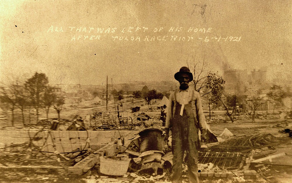 This photo provided by the Department of Special Collections, McFarlin Library, The University of Tulsa shows an unidentified man standing alone amid the ruins of what is described as his home in Tulsa, Okla., in the aftermath of the June, 1, 1921, Tulsa Race Massacre. (Department of Special Collections, McFarlin Library, The University of Tulsa via AP)