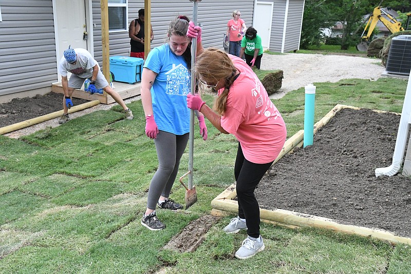 Shawnee Cooper, right, and Alexis Hicks help lay sod at 222 Eddiemee St. - Photo by Tanner Newton of The Sentinel-Record