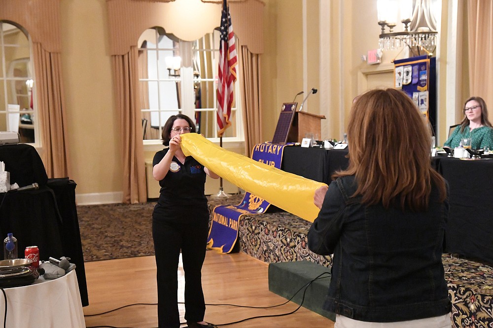 Casey Wylie, director of education at Mid-America Science Museum, does a science demonstration with Diane LaFollette, executive director of the museum, at Hot Springs National Park Rotary Club on Wednesday. - Photo by Tanner Newton of The Sentinel-Record