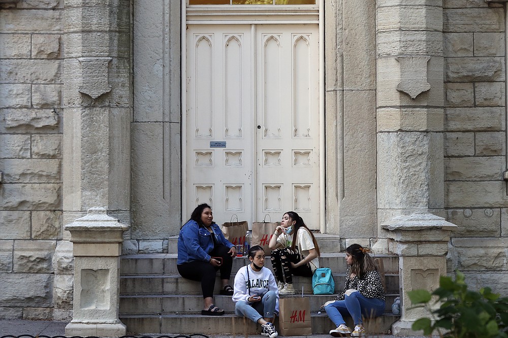 A group of shoppers sit as they take a break from shopping, Wednesday, May 26, 2021, in downtown Chicago. With vaccinations rolling out and shoppers freer to go out maskless, retailers are seeing an eager return to their stores after months of watching their customers focus on online buying during the pandemic. (AP Photo/Shafkat Anowar)