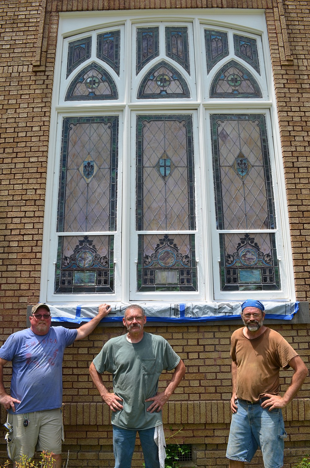(From left) Ron Dwarshak, Nathan Cathey and Ernest Waters catch their breath after re-installing freshly refurbished 1912 vintage Murano stained glass windows in newly rebuilt wooden frames. (Special to The Commercial/Richard Ledbetter)