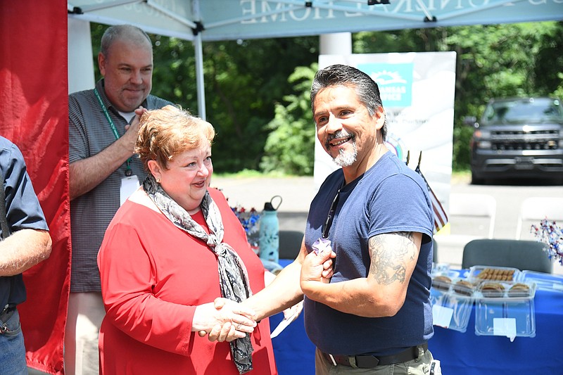 Amy Thomason, chair of the Veterans Clergy Partnership, gives a star off a retired American flag to Daniel Santos, a U.S. Army veteran, during a drive-thru event for veterans at Gross Funeral Home for Memorial Day. - Photo by Tanner Newton of The Sentinel-Record