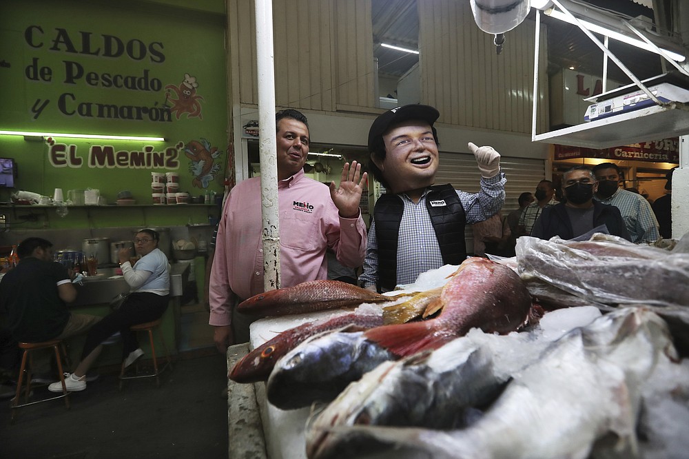Mayoral candidate Guillermo Valencia with the Institutional Revolutionary Party, PRI, campaigns at a market in Morelia, Michoacan state, Mexico, Friday, May 21, 2021. After a May 8 attack on his life that wounded his bodyguard and private secretary, the PRI candidate fears cartel gunmen will try to finish the job they botched. (AP Photo/Marco Ugarte)
