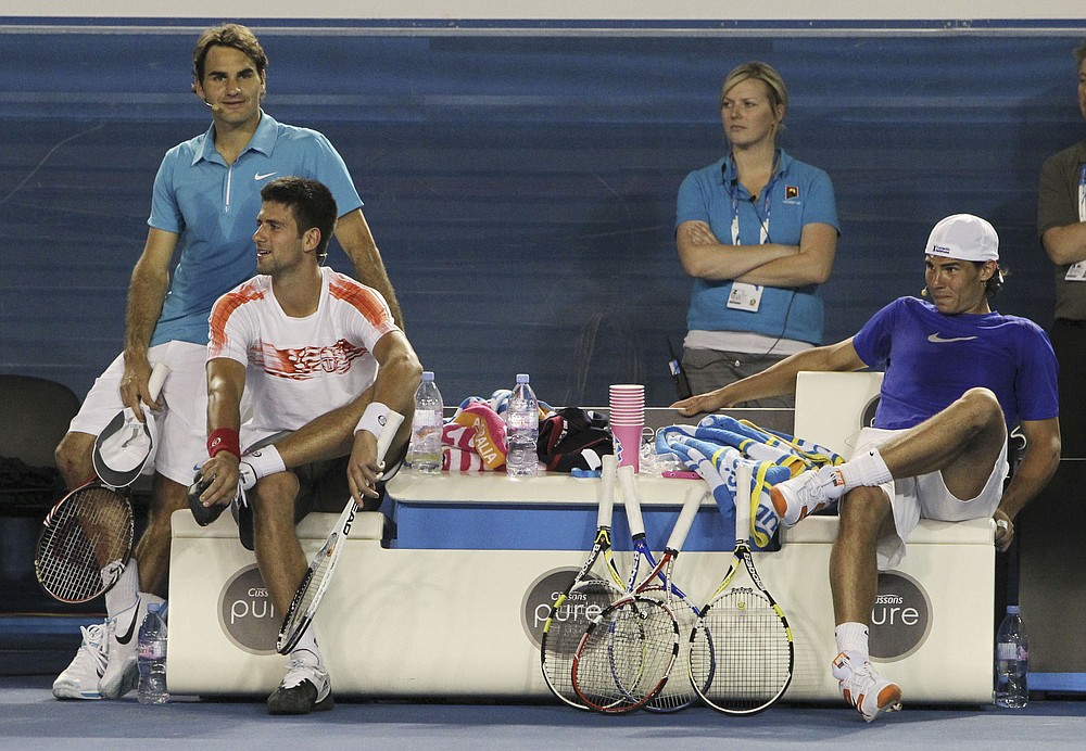 FILE - Roger Federer of Switzerland, left, Novak Djokovic of Serbia, second left, and Rafael Nadal of Spain watch an exhibition tennis match in Melbourne, Australia, in this Sunday Jan. 17, 2010, file photo. Novak Djokovic, Rafael Nadal and Roger Federer all ended up in the same half of the French Open men's field in the draw Thursday, May 27, 2021, meaning no more than one of them can reach the final. (AP Photo/Mark Baker, File)