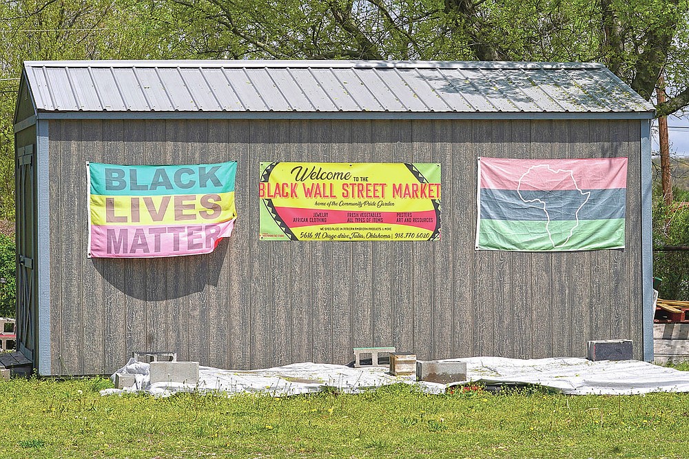 Flags hang on a shed at the Black Wall Street Market, Saturday, April 10, 2021, in Tulsa, Okla. The 6 miles between the old and new incarnations of Black Wall Street belie the dire connection that links them: Racial and socioeconomic inequality on Tulsa’s north side has its roots in the 100-year-old atrocity of the Tulsa Race Massacre. (AP Photo/Sue Ogrocki)