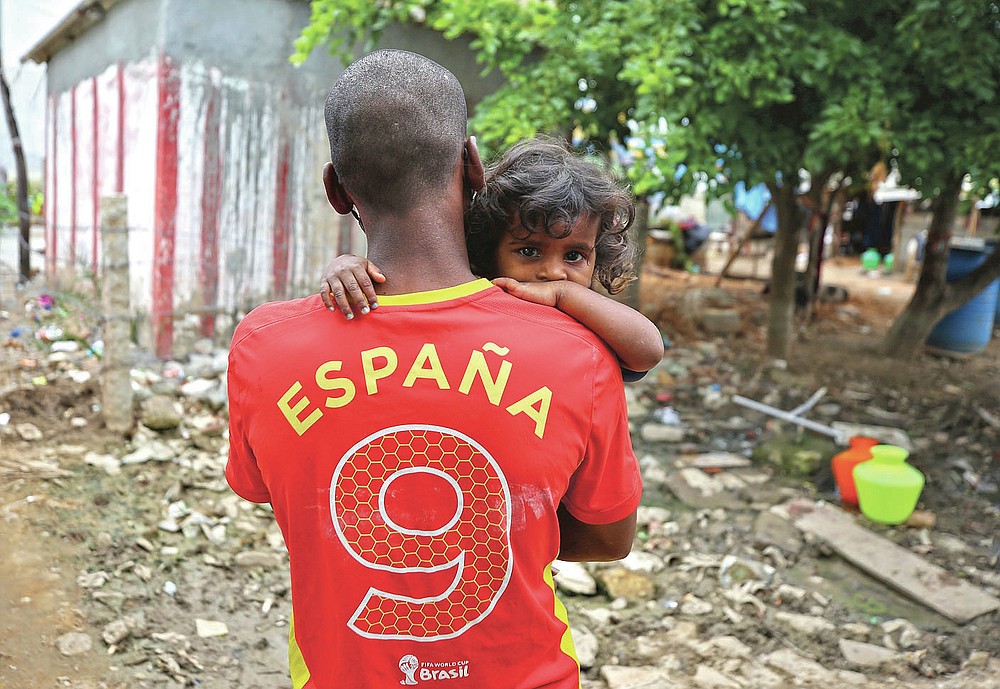 Gangaiah, son of Padmavathi who died of COVID-19, holds his two-year-old daughter Priya outside their family hut in a slum in Bengaluru, India, Thursday, May 20, 2021. Padmavathi collected hair, taking it from women's combs and hairbrushes to later be used for wigs. She earned about $50 a month. (AP Photo/Aijaz Rahi)