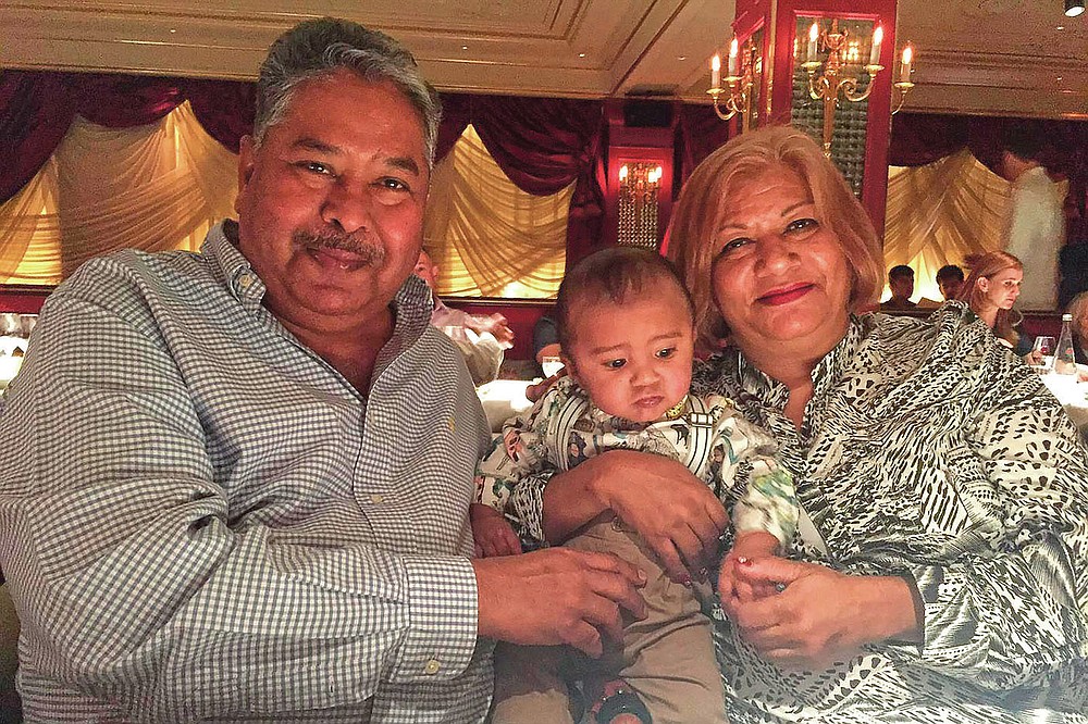 In this undated photo provided by Amrohi family, Yamini Amrohi, right, poses with her grandson and late husband Ashok Amrohi, who died of COVID-19, at a restaurant in London. Ashok, a medical doctor before joining the diplomatic corps, had traveled the world. He'd been ambassador to Algeria, Mozambique and Brunei, and had retired to Gurgaon, a city just outside the capital, and a life of golf and piano lessons. (Amrohi family via AP)