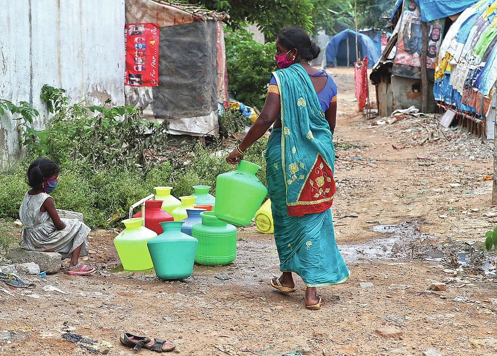 Five-year-old Shanthi, left, granddaughter of Padmavathi who died of COVID-19, collects potable water at a public tap near her family hut at a slum in Bengaluru, India, Thursday, May 20, 2021. Padmavathi collected hair, taking it from women's combs and hairbrushes to later be used for wigs. She earned about $50 a month. (AP Photo/Aijaz Rahi)