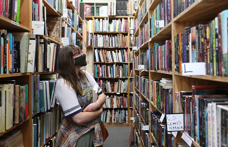 Jessica Pollard looks at a variety of books Thursday, May 27, 2021, inside the Dickson Street Bookshop in Fayetteville. The store was closed for several months during the pandemic. Government sales tax revenue kept growing. Check out nwaonline.com/210531Daily/ and nwadg.com/photos for a photo gallery.
(NWA Democrat-Gazette/David Gottschalk)