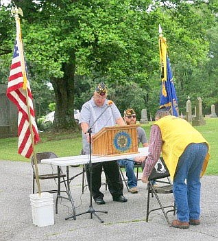 Westside Eagle Observer/SUSAN HOLLAND
Mark Russow, vice-commander of John E. Tracy American Legion Post 25 at Gravette, places the POW/MIA banner on the back of the empty chair which is a standard feature at every American Legion meeting, while post chaplain Jheri Roberts explains the significance of the tradition.