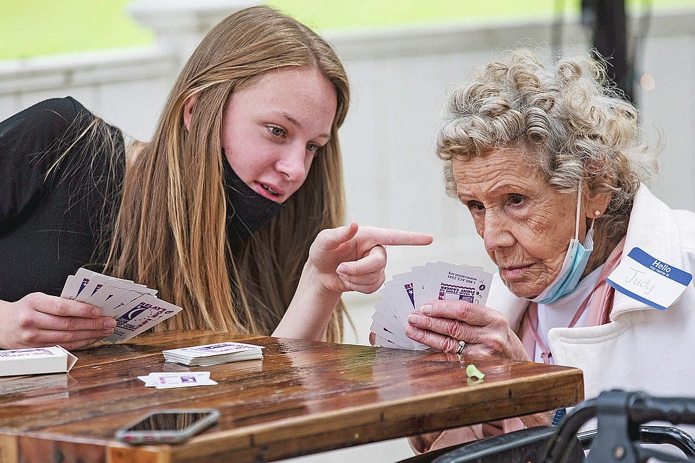 Bridget Peck teaches her pen pal Judy Kiser to play gin rummy at a reception for the Grimsley Pen Pal Club at Heritage Greens Senior Living in Greensboro, N.C., on Sunday, May 16, 2021. On Sunday, Grimsley High School students who have been corresponding with Heritage Greens seniors this school year got to meet their pen pals for the first time. (Woody Marshall/News & Record via AP)