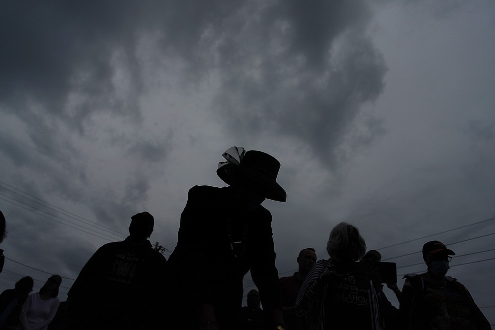 Edna Osborne, center holds her head down in prayer during the dedication of a prayer wall outside of the historic Vernon African Methodist Episcopal Church in the Greenwood neighborhood during the centennial of the Tulsa Race Massacre, Monday, May 31, 2021, in Tulsa, Okla. The church was largely destroyed when a white mob descended on the prosperous Black neighborhood in 1921, burning, killing, looting and leveling a 35-square-block area. (AP Photo/John Locher)