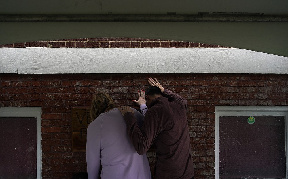 Faith Hailey, left, and Brian Hailey touch hold their hands on a prayer wall outside of the historic Vernon African Methodist Episcopal Church in the Greenwood neighborhood during the centennial of the Tulsa Race Massacre, Monday, May 31, 2021, in Tulsa, Okla. The church was largely destroyed when a white mob descended on the prosperous Black neighborhood in 1921, burning, killing, looting and leveling a 35-square-block area. (AP Photo/John Locher)