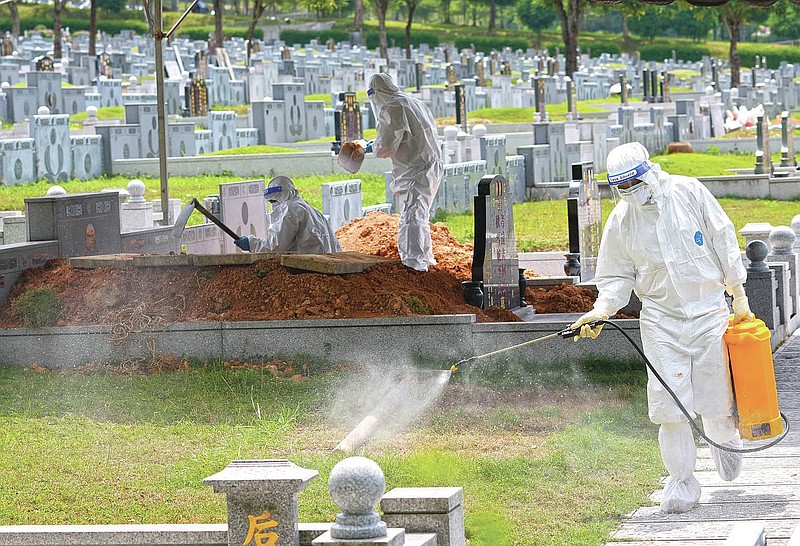 Health workers wearing Personal Protective Equipment (PPE) sanitize a field during the funeral for a COVID-19 victim at Nirvana memorial, a Buddhist, Taoist and Christian cemetery in Semenyih, Malaysia, Wednesday, May 26, 2021. Malaysia's latest coronavirus surge has been taking a turn for the worse as surging numbers and deaths have caused alarm among health officials, while cemeteries in the capital are dealing with an increasing number of deaths. (AP Photo/Vincent Thian)