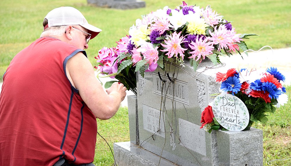 Westside Eagle Observer/MIKE ECKELS
A family member adjusts the flowers on Arlis Mae Kincheloe's headstone as other family members gathered at Decatur Cemetery Saturday morning to remember their loved ones. Families gathered Memorial Day to remember this country's veterans who made the ultimate sacrifice in defense of our freedom.