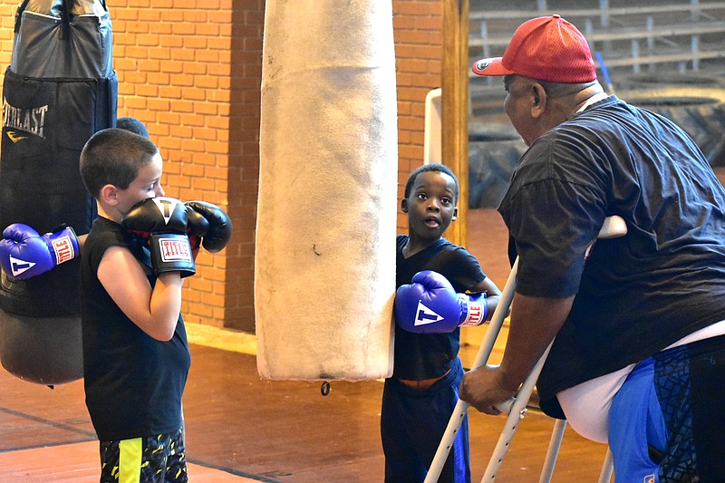 Gloves Not Guns founder and coach Albert Brewer gives jab instructions to Wes Carmical, 9, left, and Darrion White, 10, during practice Tuesday at the Southeast Middle School gymnasium. (Pine Bluff Commercial/I.C. Murrell)