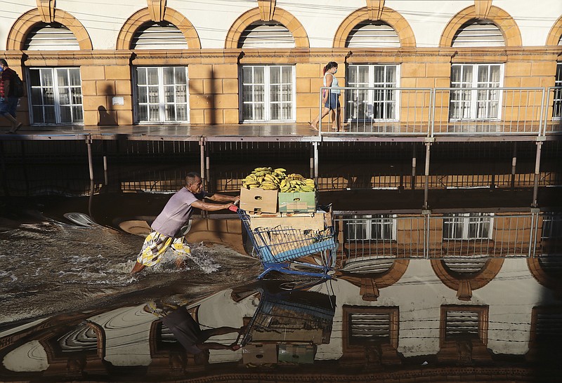 A man pushes a shopping cart loaded with bananas on a street flooded by the Negro River, in downtown Manaus, Amazonas state, Brazil, Tuesday, June 1, 2021. Rivers around Brazil's biggest city in the Amazon rain forest have swelled to levels unseen in over a century of record-keeping, according to data published Tuesday by Manaus' port authorities. (AP Photo/Edmar Barros)