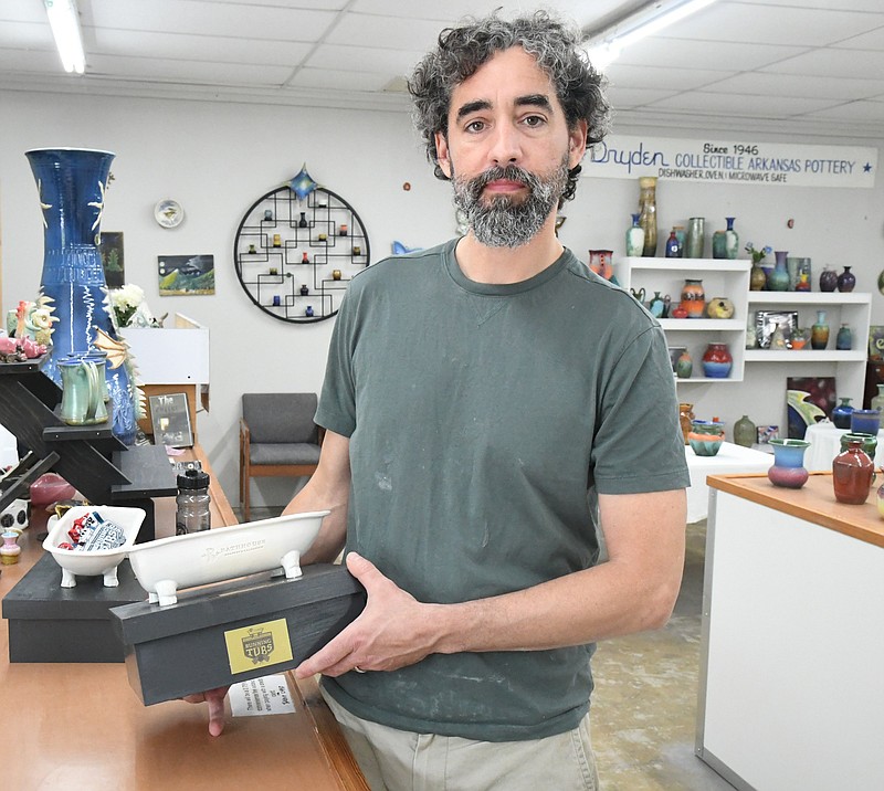 Zack Dryden, of Dryden Pottery, holds a trophy he created for The Stueart Pennington World Championship Running of the Tubs. - Photo by Tanner Newton of The Sentinel-Record