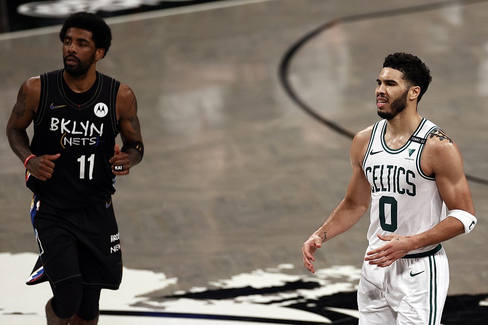 Boston Celtics forward Jayson Tatum (0) reacts in front of Brooklyn Nets guard Kyrie Irving in the second half of Game 5 during an NBA basketball first-round playoff series, Tuesday, June 1, 2021, in New York.  (AP Photo/Adam Hunger)