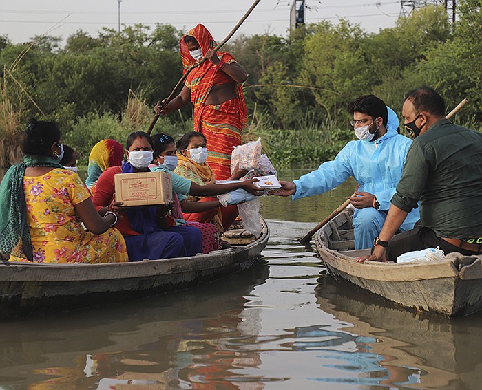 An Indian who gave his name as Himanshu distributes free aid Wednesday to people on a small island in River Yamuna at New Delhi. India continues to have high numbers of coronavirus cases.
(AP/Amit Sharma)