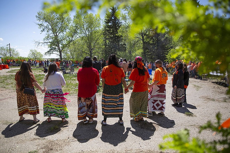 Attendees perform a round dance during a press conference and prayer vigil at the former Muscowequan Indian Residential School, one of the last residential schools to close its doors in Canada in 1997 and the last fully intact residential school still standing in Saskatchewan at Muskowekwan First Nation, Saskatchewan, Tuesday, June 1, 2021. The vigil was in response to the remains of 215 children recently found at the Kamloops Indian Residential School. (Kayle Neis/The Canadian Press via AP)