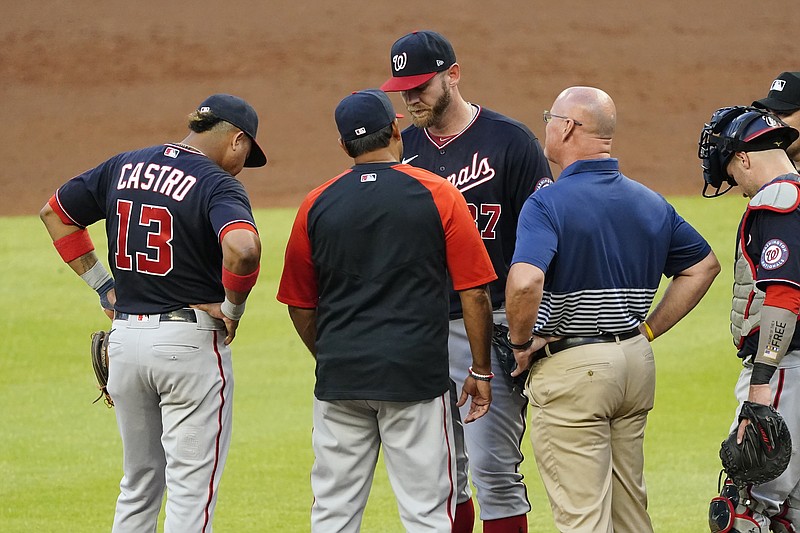 Washington Nationals starting pitcher Stephen Strasburg, center, talks with manager Dave Martinez and a member of the team's medical staff before exiting a baseball game in then second inning against Atlanta Braves Tuesday, June 1, 2021, in Atlanta. (AP Photo/John Bazemore)