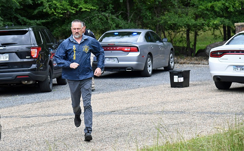 An Arkansas State Police investigator sprints to his car close to the scene of a shooting involving a trooper near 580 Woodview Lane on Wednesday. - Photo by Tanner Newton of The Sentinel-Record