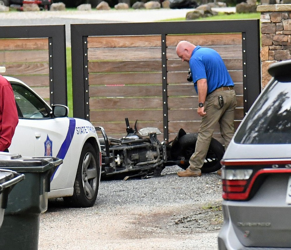 An Arkansas State Police investigator looks over an abandoned motorcycle believed to belong to a fleeing suspect at 614 Woodview Lane on Wednesday. - Photo by Tanner Newton of The Sentinel-Record