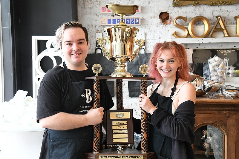 Derek Knight, left, and Emma Forbes, both of Bathhouse Soapery, hold the trophy for The Stueart Pennington World Championship Running of the Tubs. The soap shop is the sponsor of the race and the defending champion. - Photo by Tanner Newton of The Sentinel-Record